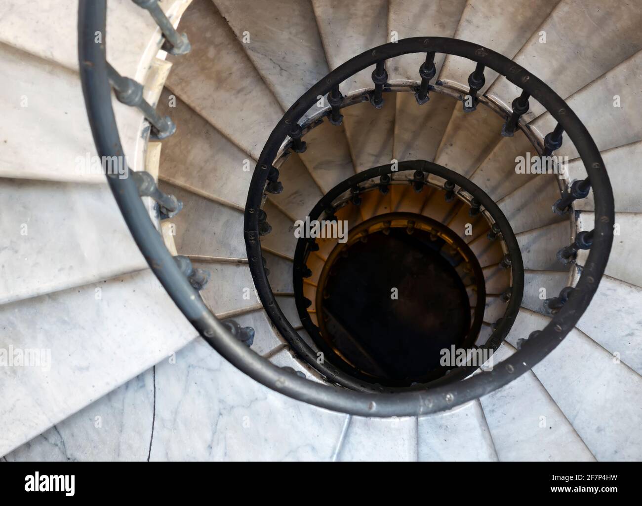 Ancien escalier en colimaçon avec marches en marbre et main courante en fer forgé. Architecture et formes incurvées. Vue de dessus vers le bas. Effet hauteur et vertige Banque D'Images