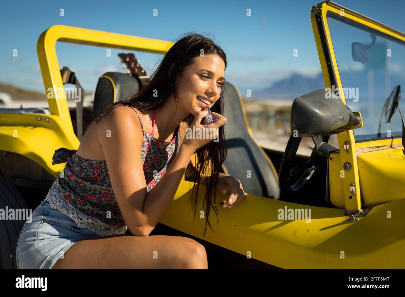 Bonne femme caucasienne s'est penchée contre le buggy de plage au bord de  la mer mettre le rouge à lèvres Photo Stock - Alamy