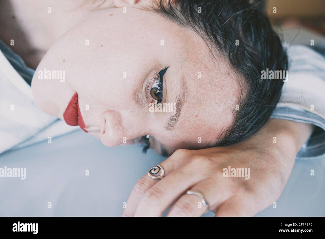 Portrait d'une jeune femme penchée son visage contre un table en verre froid Banque D'Images
