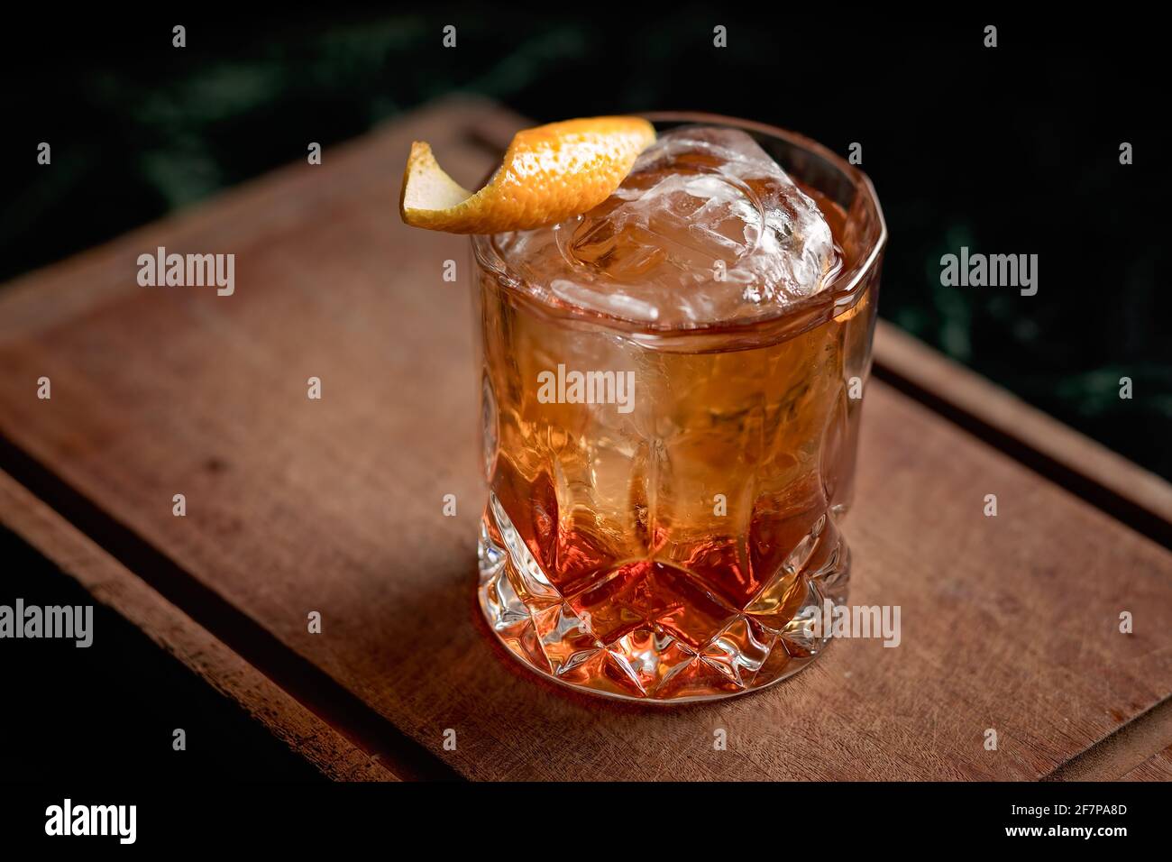 Un cocktail classique à l'ancienne servi avec une boule de glace dans un magnifique verre de roche, avec une pelure d'orange comme garniture. Banque D'Images