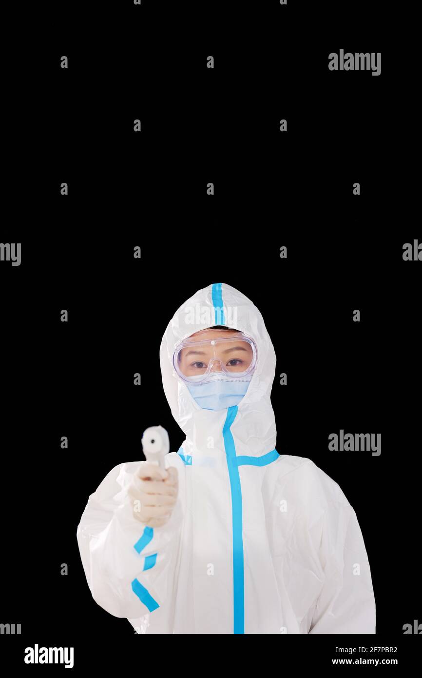 Une femme médecin en vêtements de protection médicale prend de la température Banque D'Images