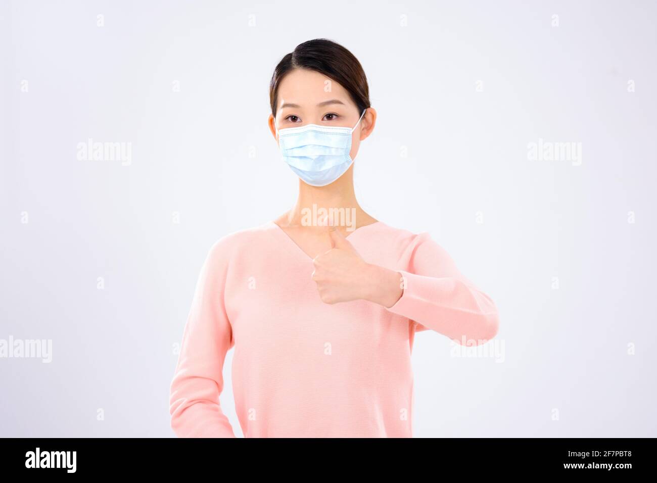 Une jeune femme avec un masque a tenu son pouce vue avant Banque D'Images