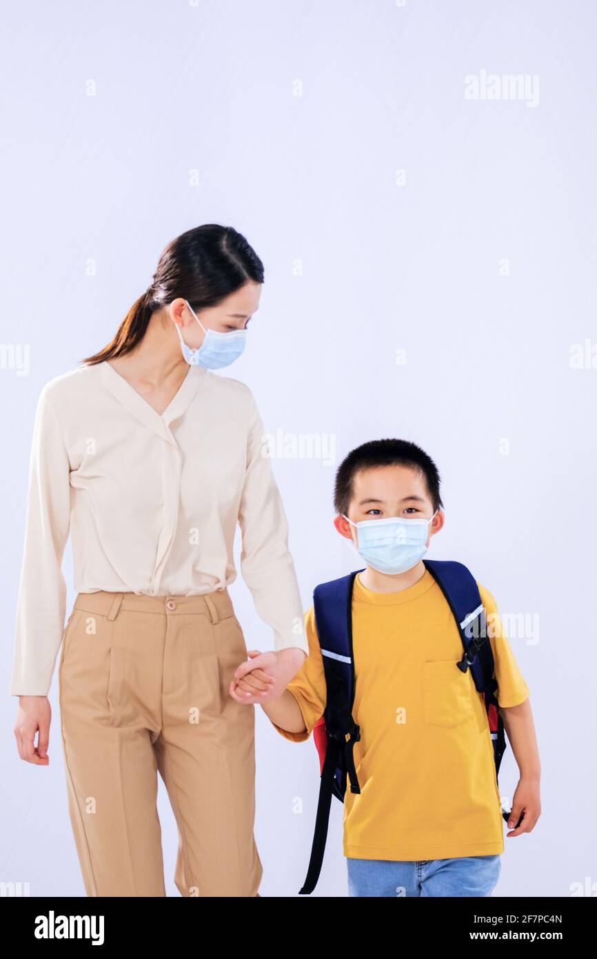 La mère a envoyé le petit garçon avec le masque à la main de l'école en main Banque D'Images
