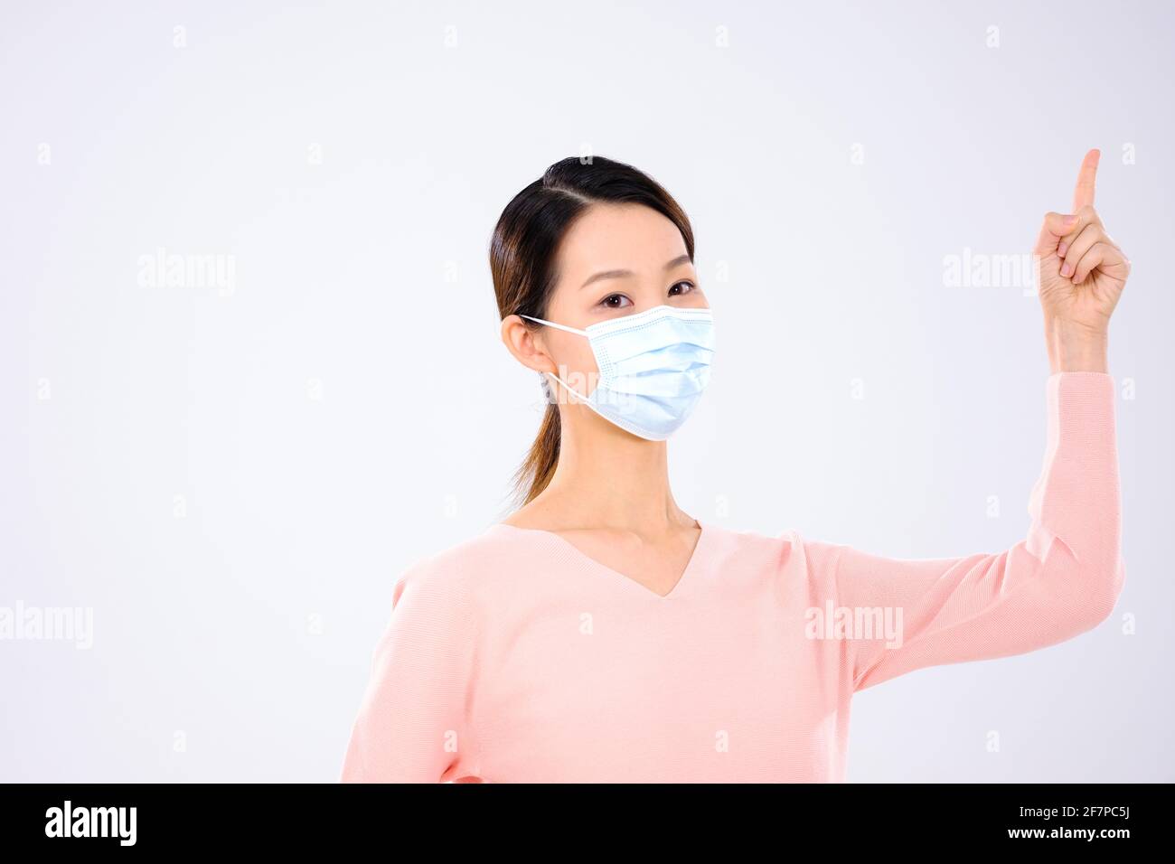 Une jeune femme avec un masque pointant vers le haut Banque D'Images