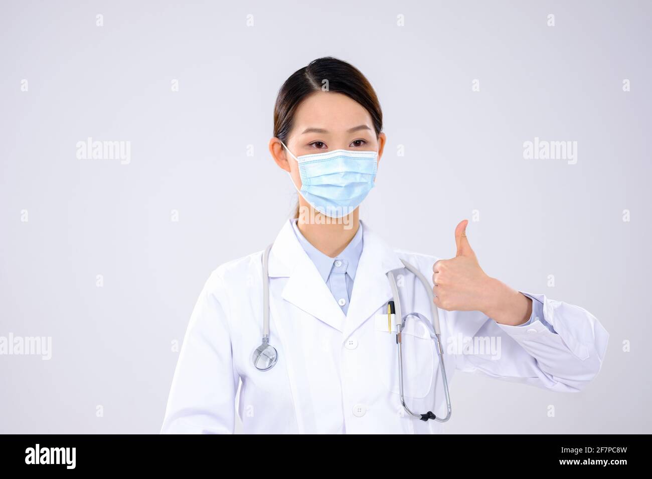 Une femme médecin avec un masque a tenu son pouce vue avant Banque D'Images