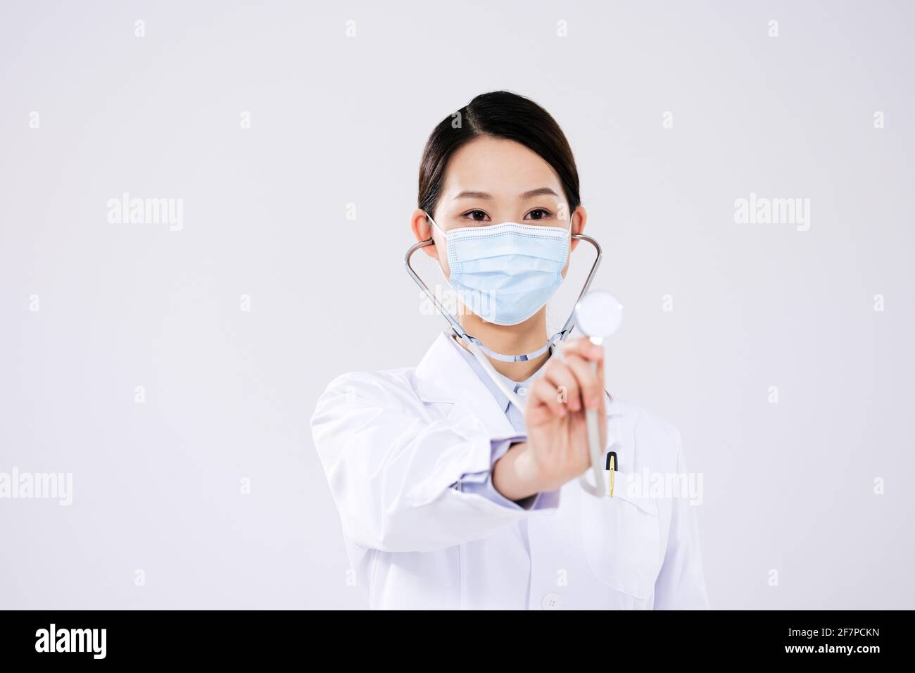 Une femme médecin portant un masque utilise un stéthoscope avant vue Banque D'Images