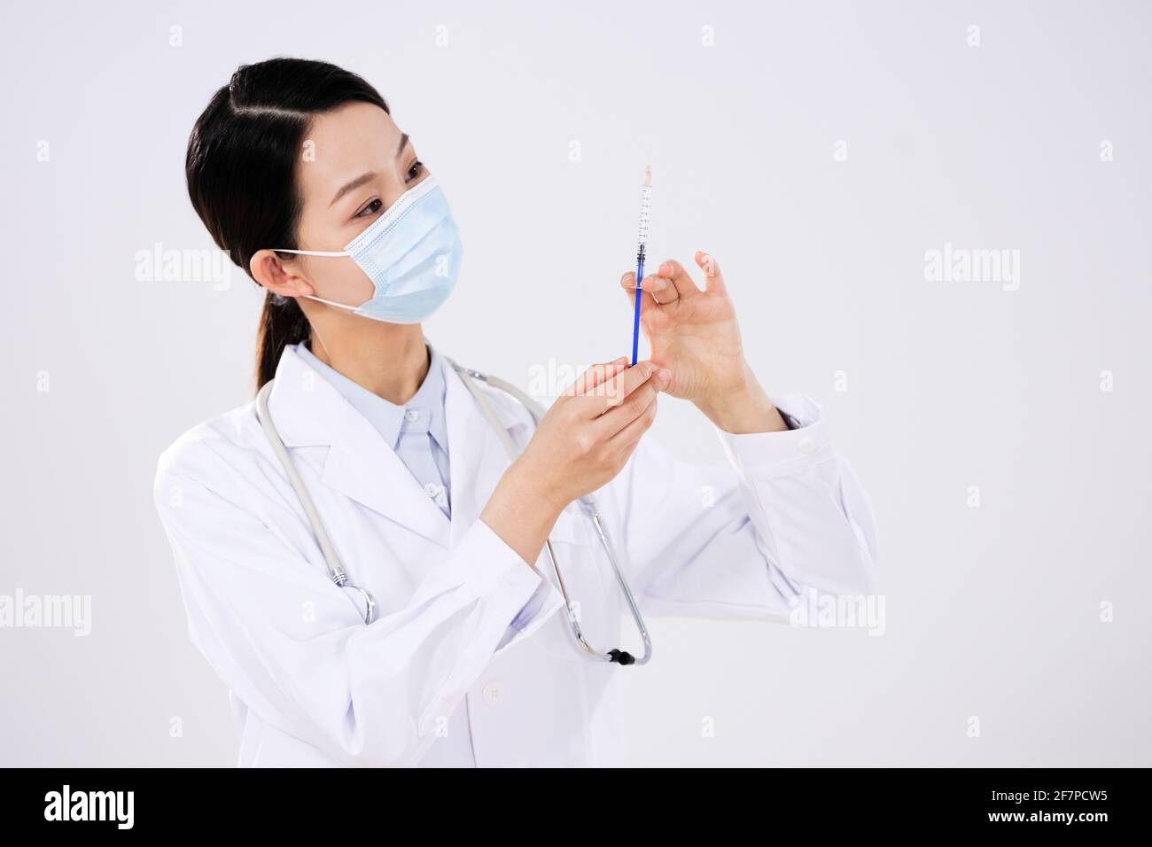 Une femme médecin avec un masque utilise une seringue non regarder la caméra Banque D'Images
