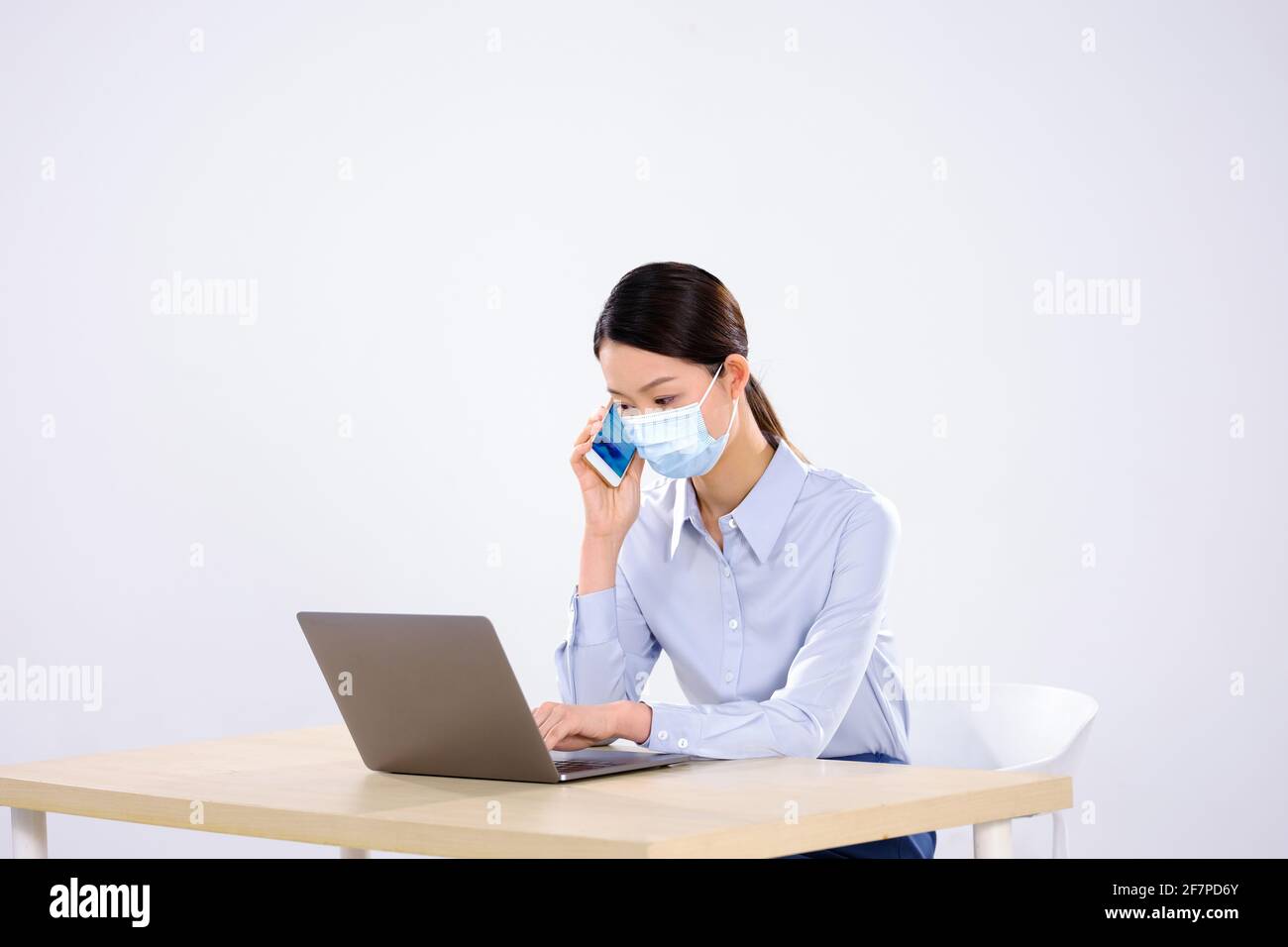 Une jeune femme avec un masque est au téléphone dans la vue latérale du bureau Banque D'Images