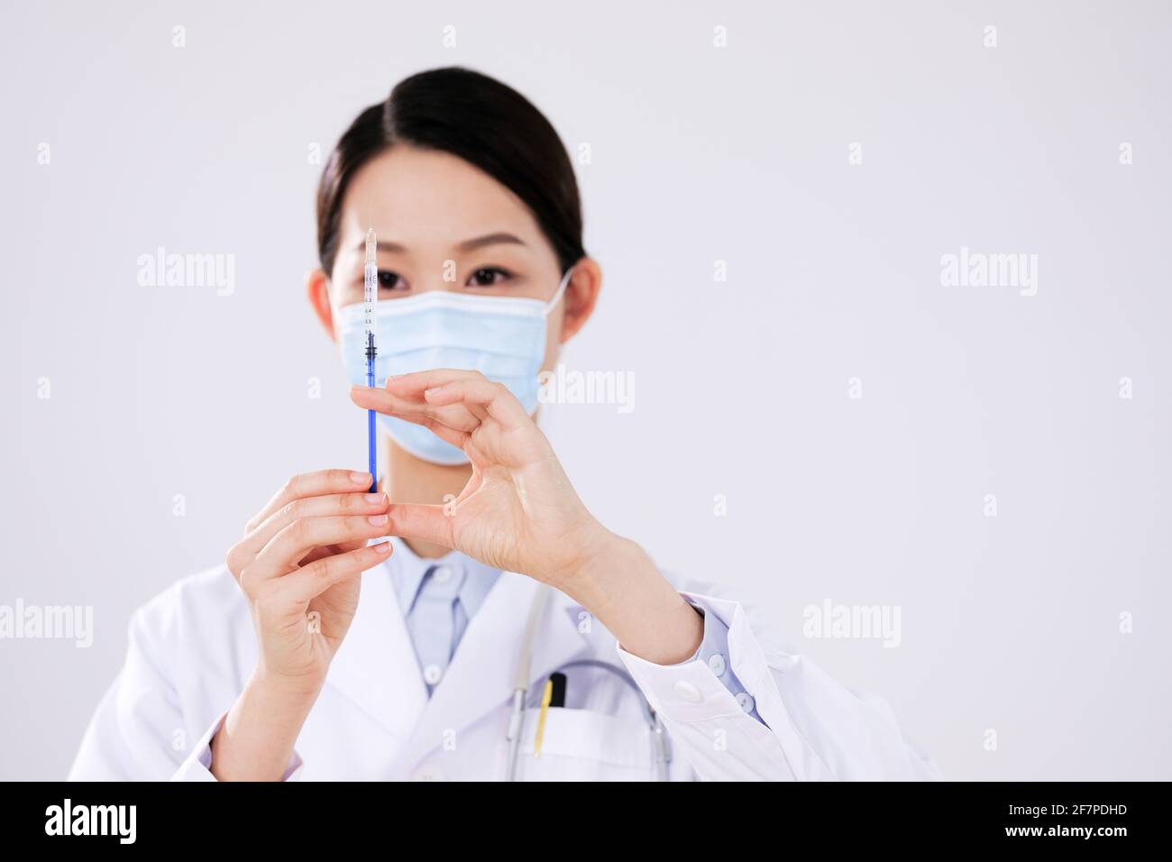 Une femme médecin avec un masque utilise un front de seringue vue Banque D'Images