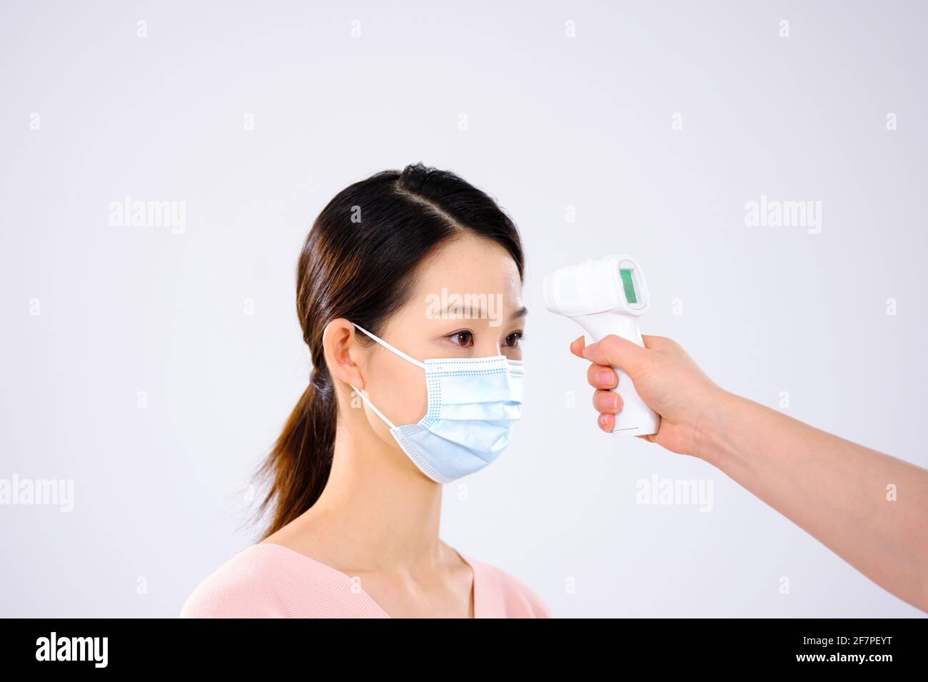 Une jeune femme avec un masque a pris son côté température vue Banque D'Images