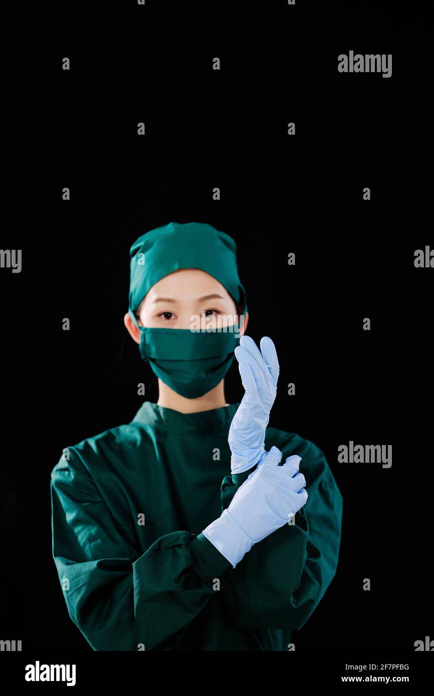 Une jeune femme chirurgien portait des gants chirurgicaux en regardant le appareil photo Banque D'Images