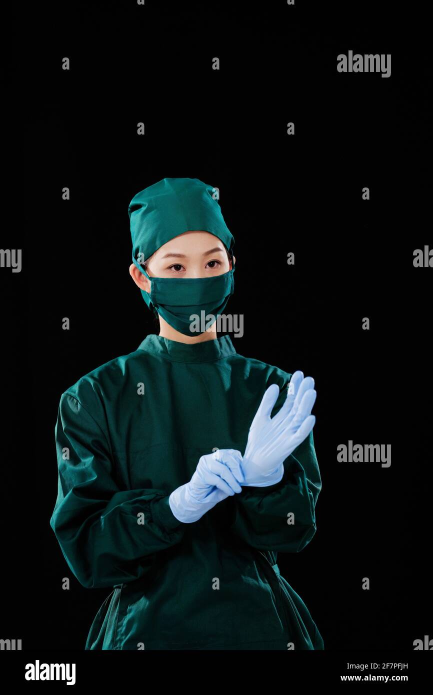Une jeune femme chirurgien portait des gants chirurgicaux en regardant le appareil photo Banque D'Images