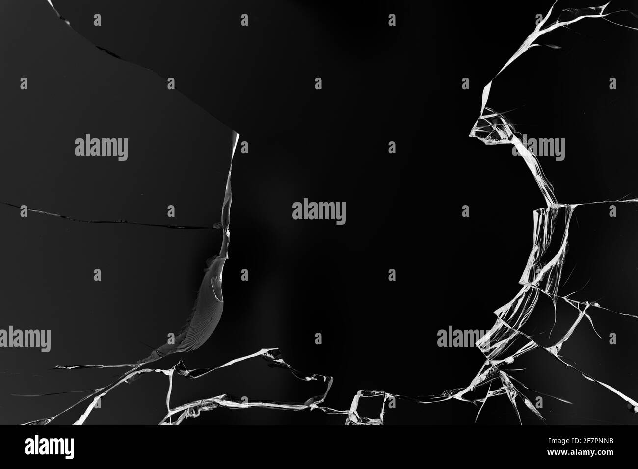 Fissures dans le verre, avec trous de balles sur fond noir. Banque D'Images