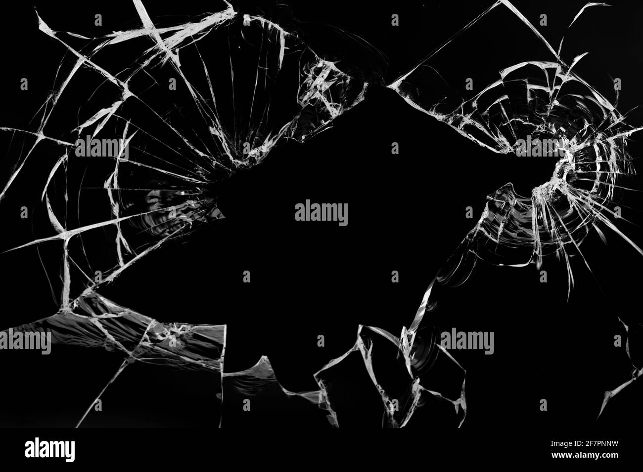 Fissures dans le verre, avec trous de balles sur fond noir. Banque D'Images