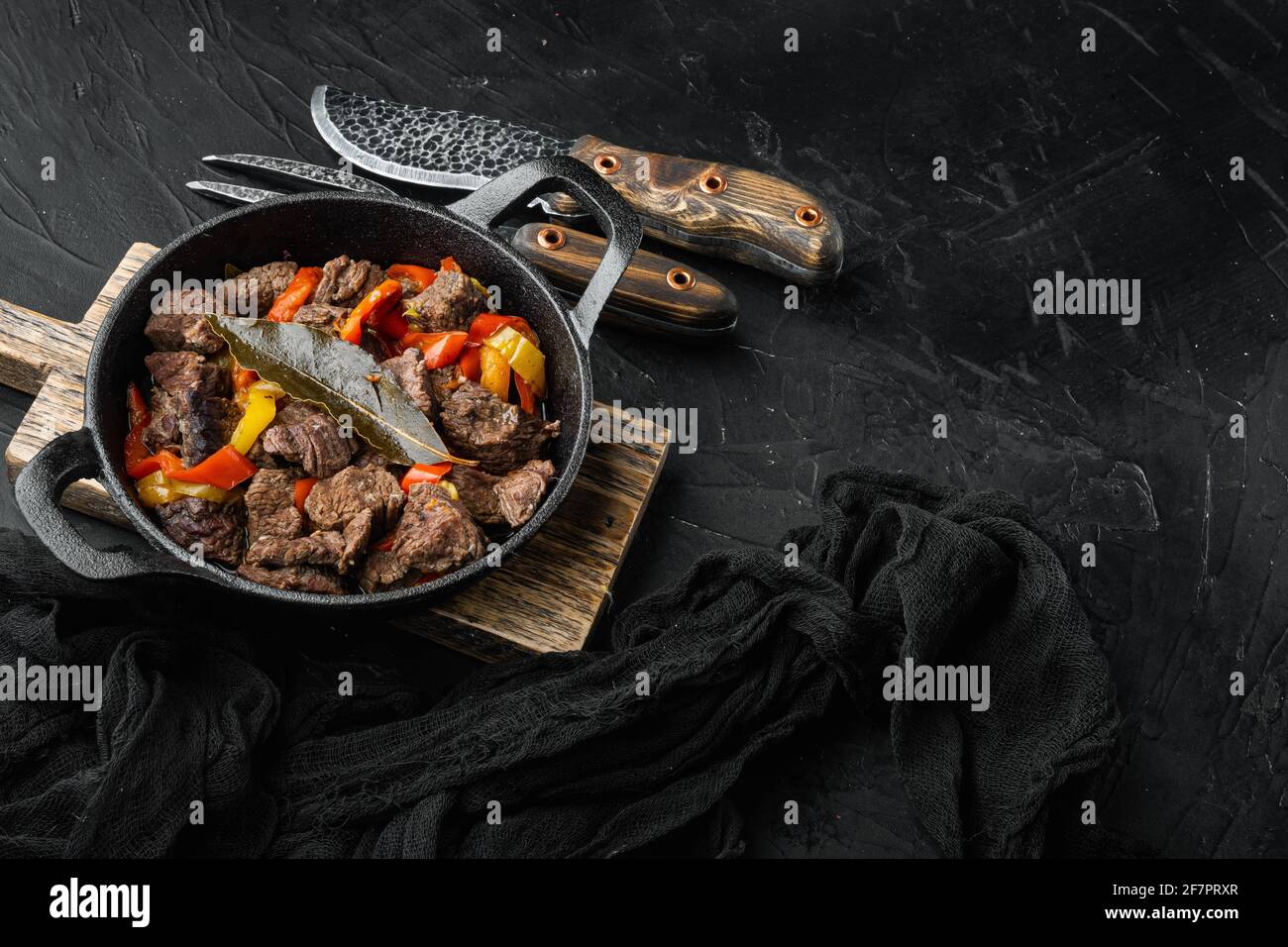 Ragoût de viande de boeuf et de légumes servi, dans une poêle en fonte, sur fond de pierre noire, avec un espace de copie pour le texte Banque D'Images