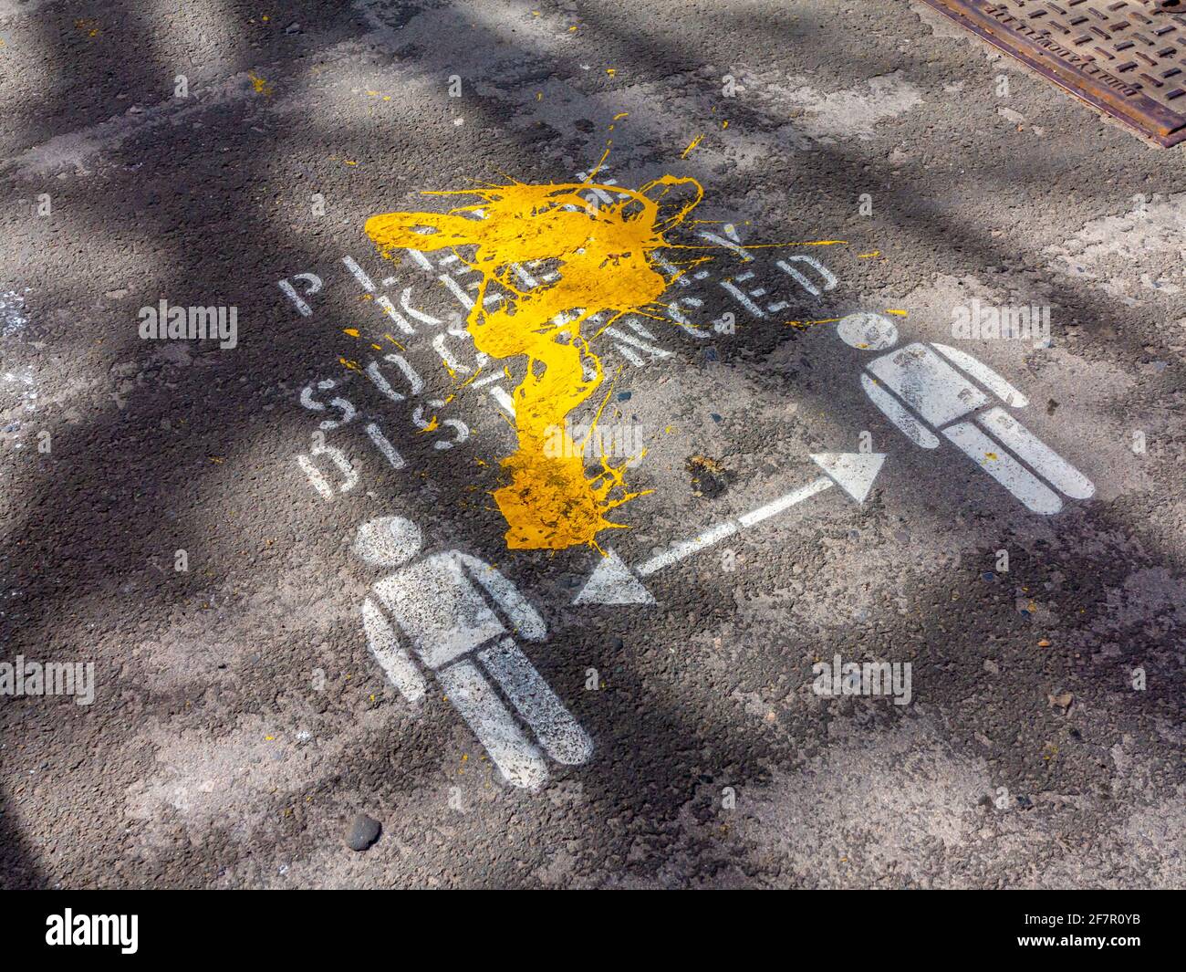 Peinture jaune au dessus de s'il vous plaît garder social distancé signe sur un trottoir dans le bain de Matlock Derbyshire Angleterre en avril 2021. Banque D'Images