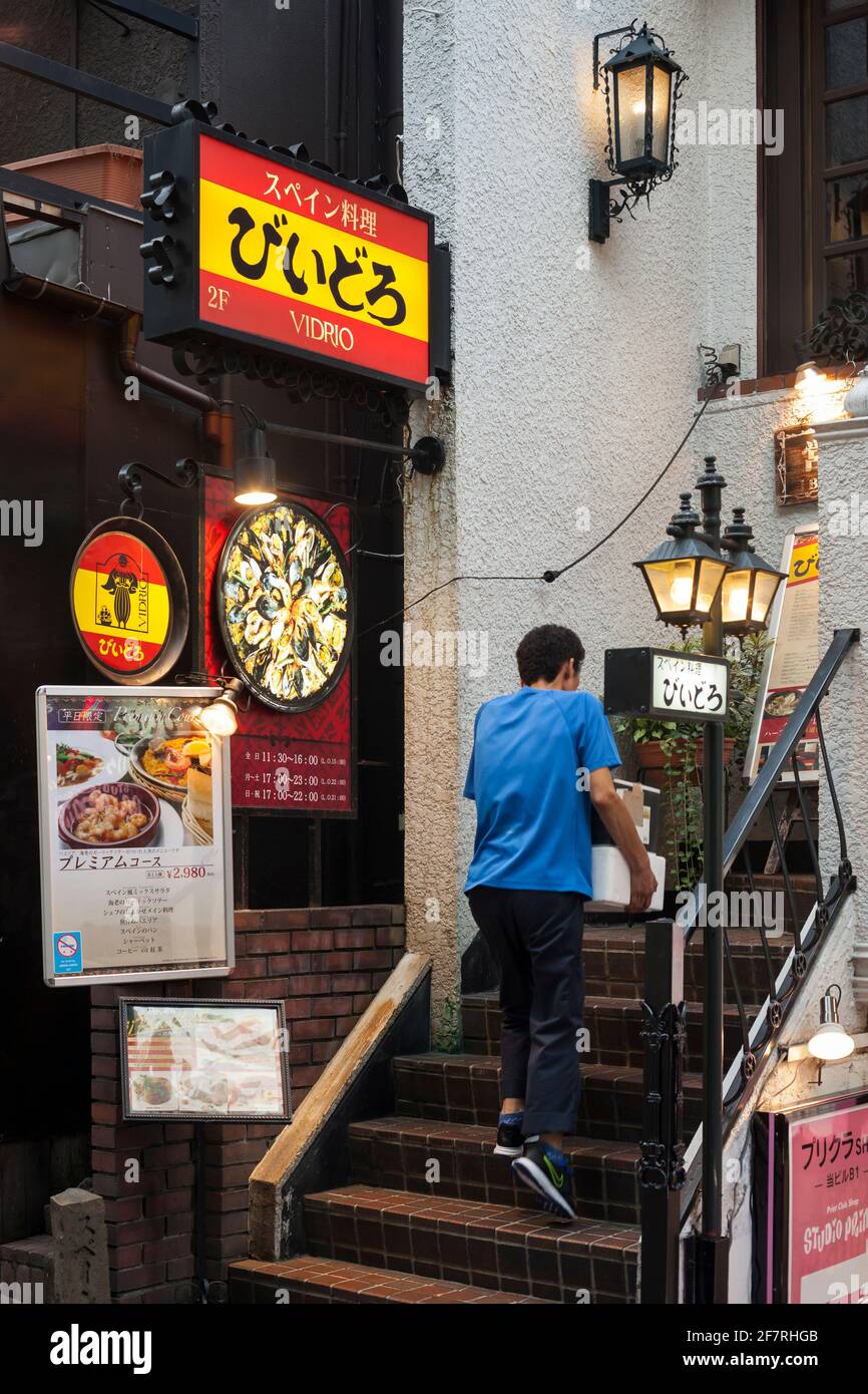 Vue verticale d'un livreur montant les escaliers d'un restaurant espagnol sur Shibuya Centre-gai, Shibuya, Tokyo, Japon Banque D'Images