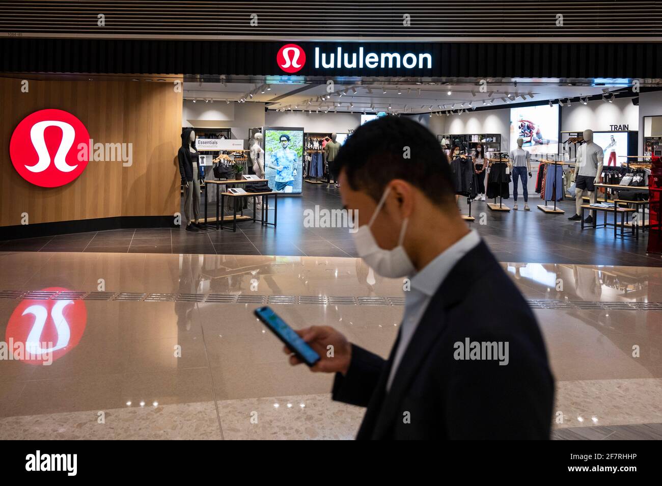 Un acheteur portant un masque passe devant la bande de vêtements de sport canadiens, le logo Lululemon et le magasin à Hong Kong. Banque D'Images