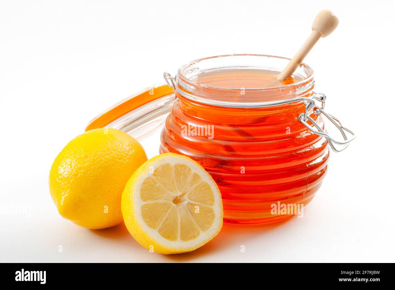 Traitement du rhume et de la grippe, remède naturel d'hiver et concept de médecine traditionnelle avec un pot ou un pot de miel, un égouttoir de miel et un citron en tranches isolé sur W Banque D'Images