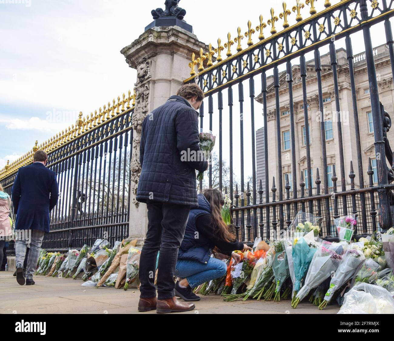 Londres, Royaume-Uni. 9 avril 2021. Un couple a posé des fleurs en hommage au prince Philip à l'extérieur de Buckingham Palace. Le duc d'Édimbourg est mort aujourd'hui, âgé de 99 ans. Credit: Vuk Valcic/Alamy Live News Banque D'Images