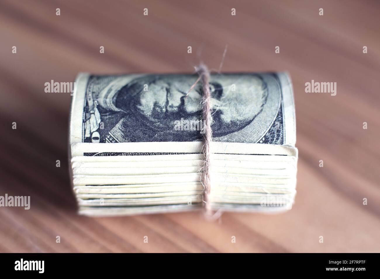 Les dollars AMÉRICAINS se sont mis à rouler et se sont resserrés avec un bracelet isolé table en bois Banque D'Images