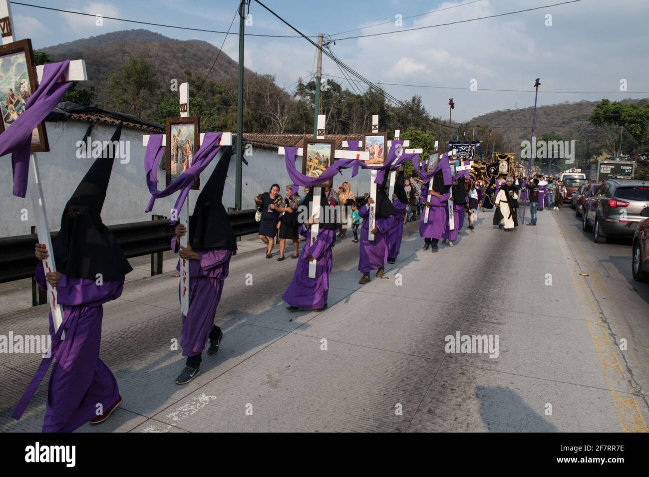 Les pénitents à capuche portent des croix lors de la procession Semana Santa à Antigua, Guatemala, une tradition solennelle de Carême reflétant la passion du Christ. Banque D'Images