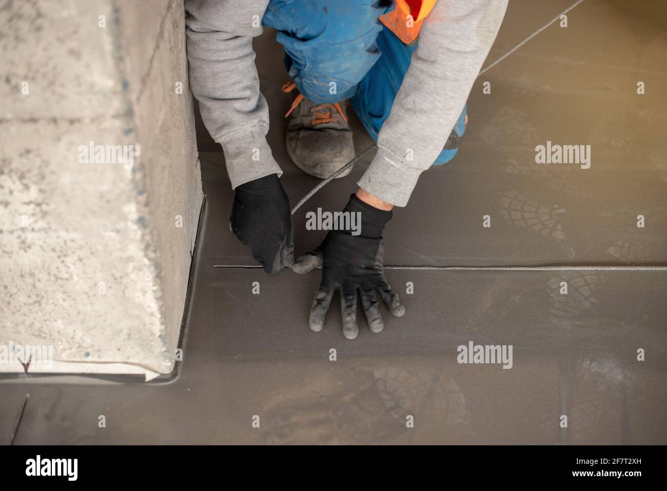 Travailleur travaillant au sol d'un bâtiment industriel. Travailleur de la construction produisant du coulis et finissant des sols humides en béton. Banque D'Images