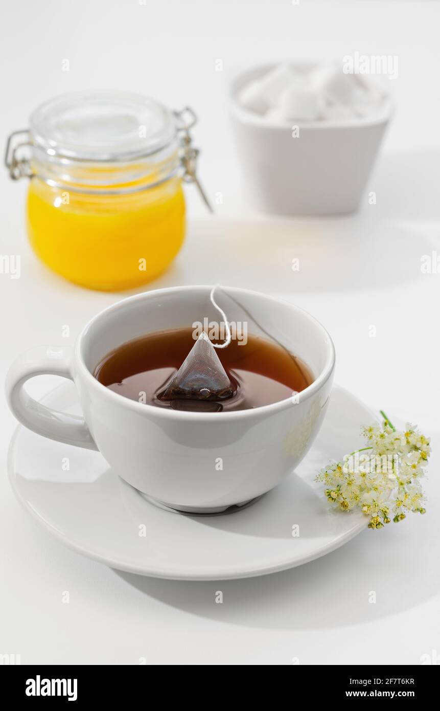 Une tasse de thé chaud est préparée dans un sachet de thé. Fleurs sur une  soucoupe, miel et sucre en arrière-plan. Faible profondeur de champ Photo  Stock - Alamy
