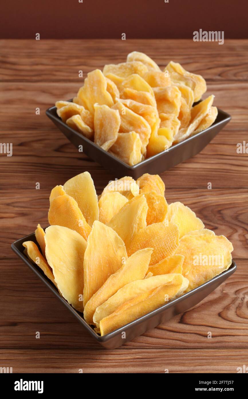 Morceaux séchés de mangue et de jackfruit sur une table en bois, placés sur des bols en céramique marron. Macro. Gros plan Banque D'Images