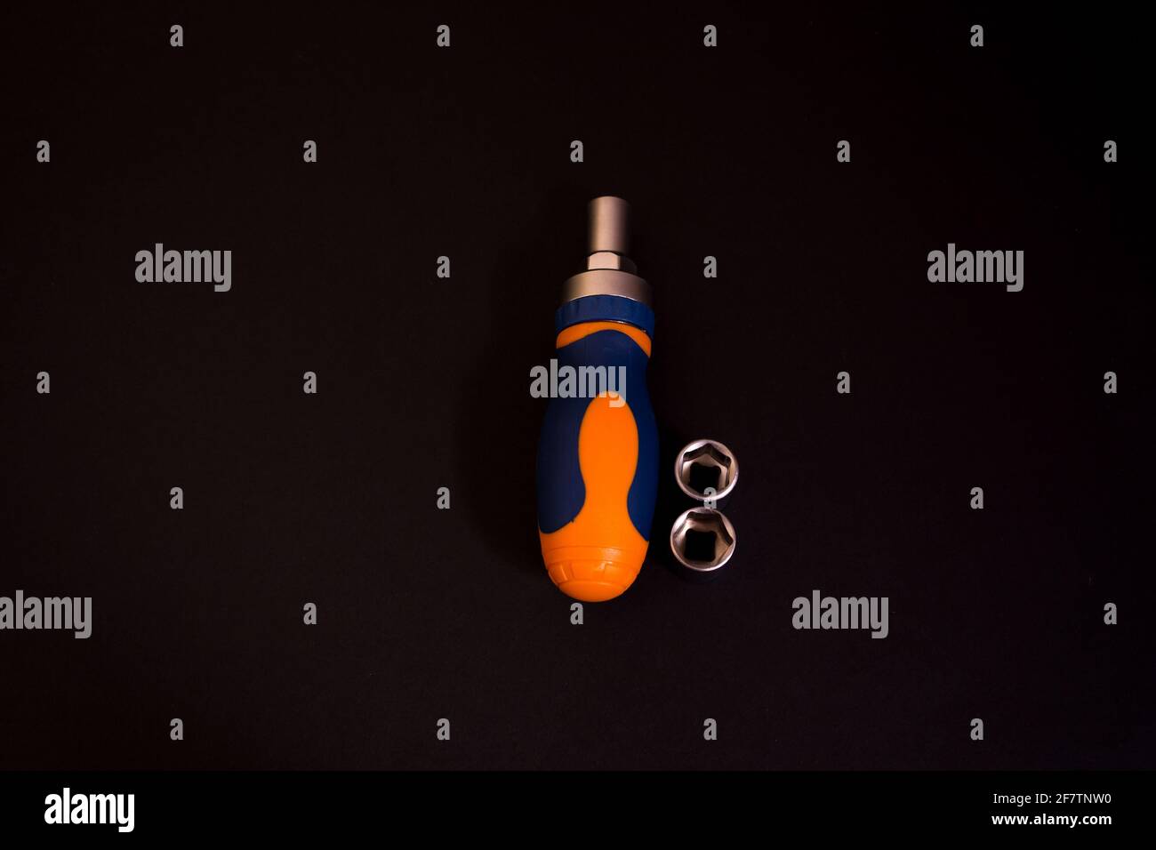 Gros plan d'un tournevis bleu et orange avec adaptateurs isolé sur fond noir Banque D'Images