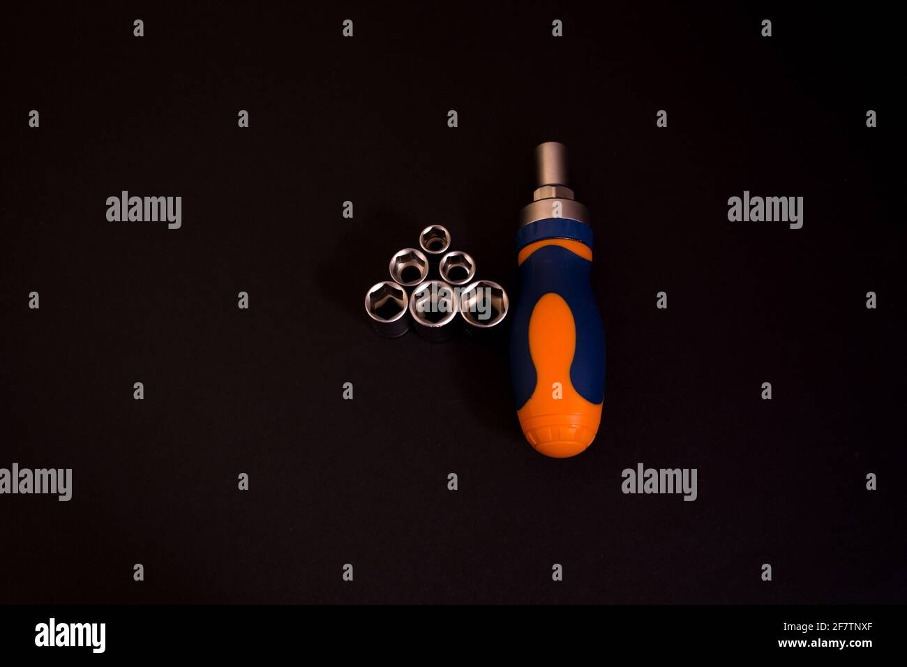 Gros plan d'un tournevis bleu et orange avec adaptateurs isolé sur fond noir Banque D'Images