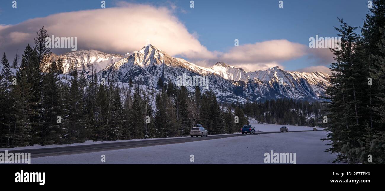 Autoroute avec voitures traversant Banff avec chaîne de montagnes enneigée Banque D'Images