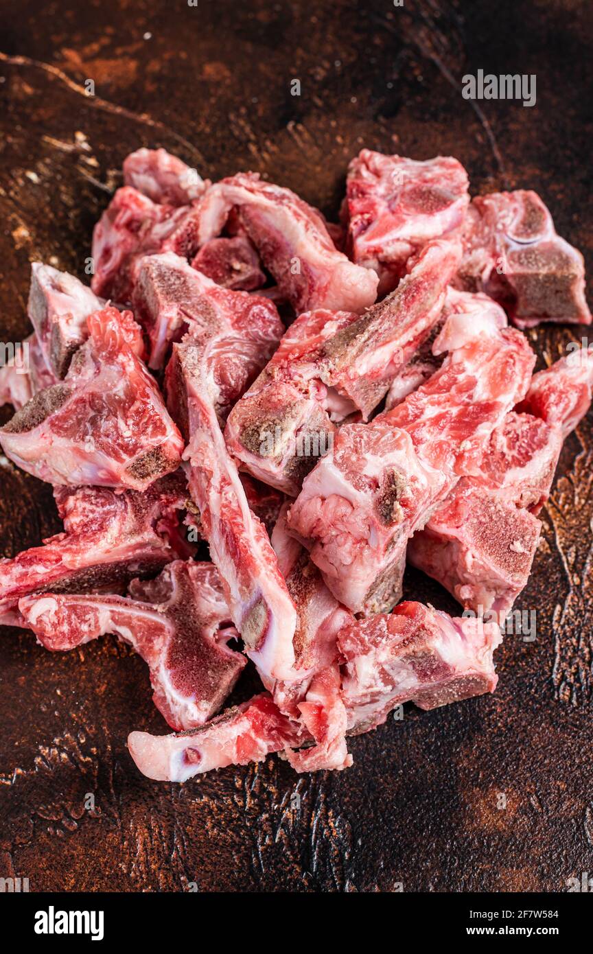 Viande crue sur l'os coupée en dés pour ragoût. Arrière-plan sombre. Vue de dessus Banque D'Images