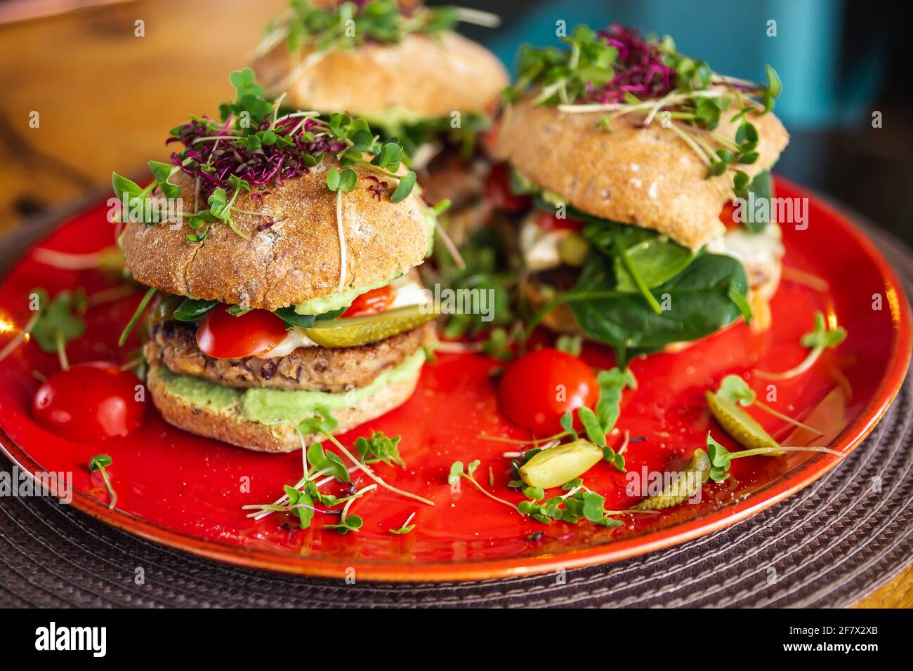 Burgers de pois chiches végétaliens avec des arugula, des concombres marinés, des tomates et de l'avocat sur la table Banque D'Images