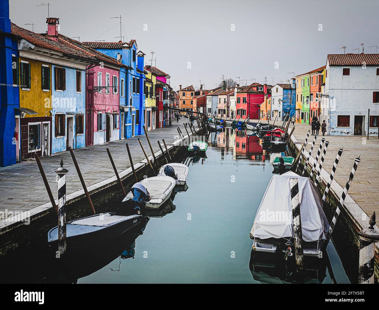 Bateaux amarrés et maisons colorées dans un canal maisons de rue sur l'île de Burano, Venise, une personne méconnaissable sur le fond. Banque D'Images