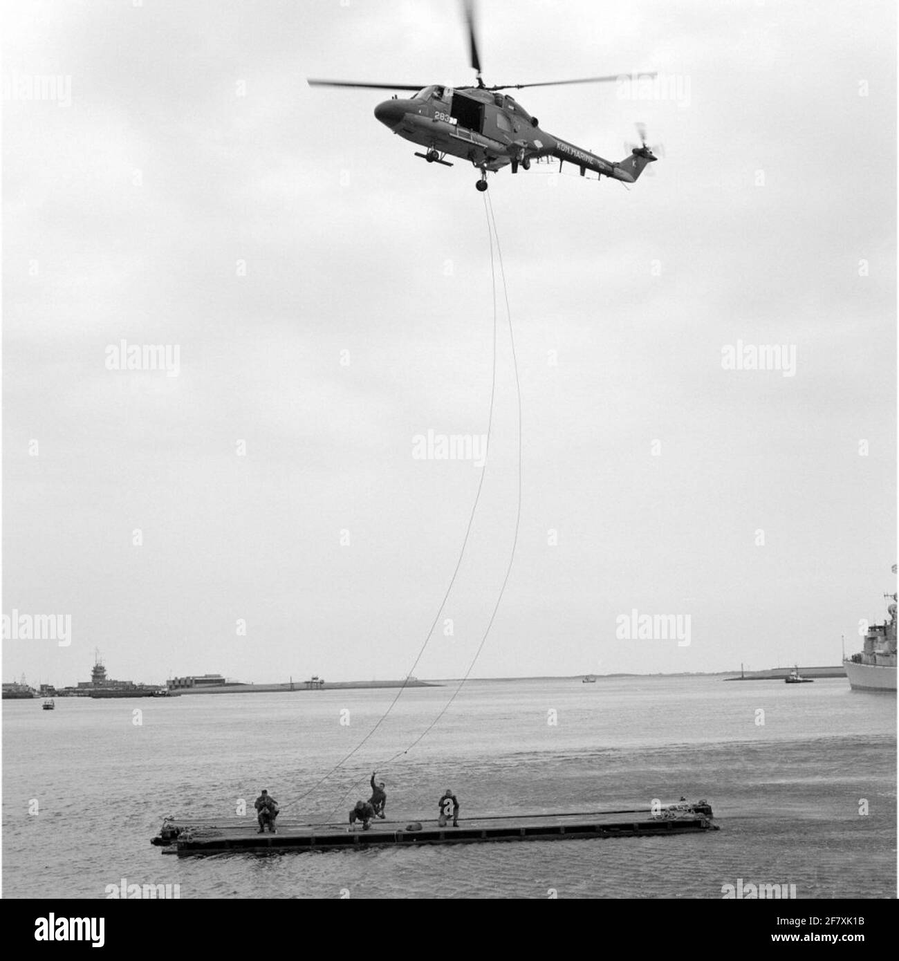 Les personnes qui font de l'exercice déposent sur une plate-forme flottante avec l'élingue (câble de levage) de l'hélicoptère Westland SH-14D Navy Lynx portant l'immatriculation 283 (env. 1981 2012) en mai 1990. Banque D'Images