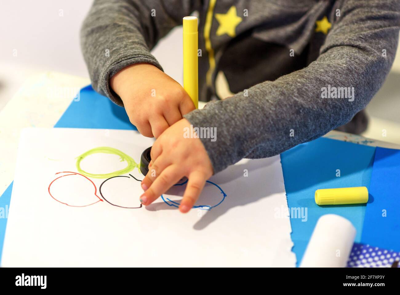 Petite enfant peinture avec la pointe tombée stylos anneaux colorés sur le papier. Banque D'Images