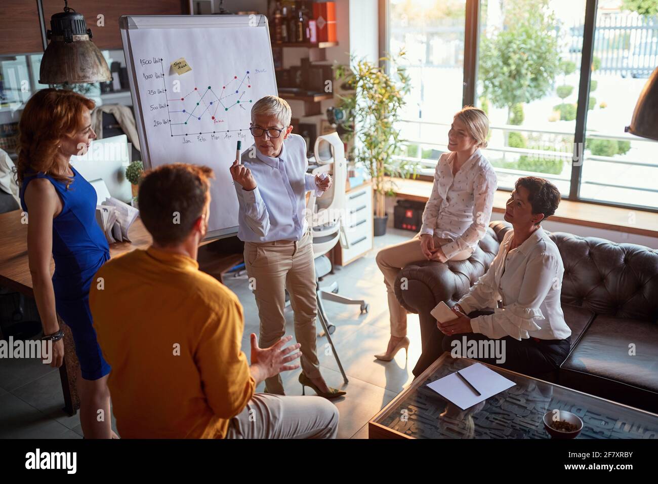 Un patron féminin âgé a un débat avec son jeune collègue masculin tout en tenant une réunion dans une atmosphère tendue sur le lieu de travail. Affaires, bureau, travail Banque D'Images