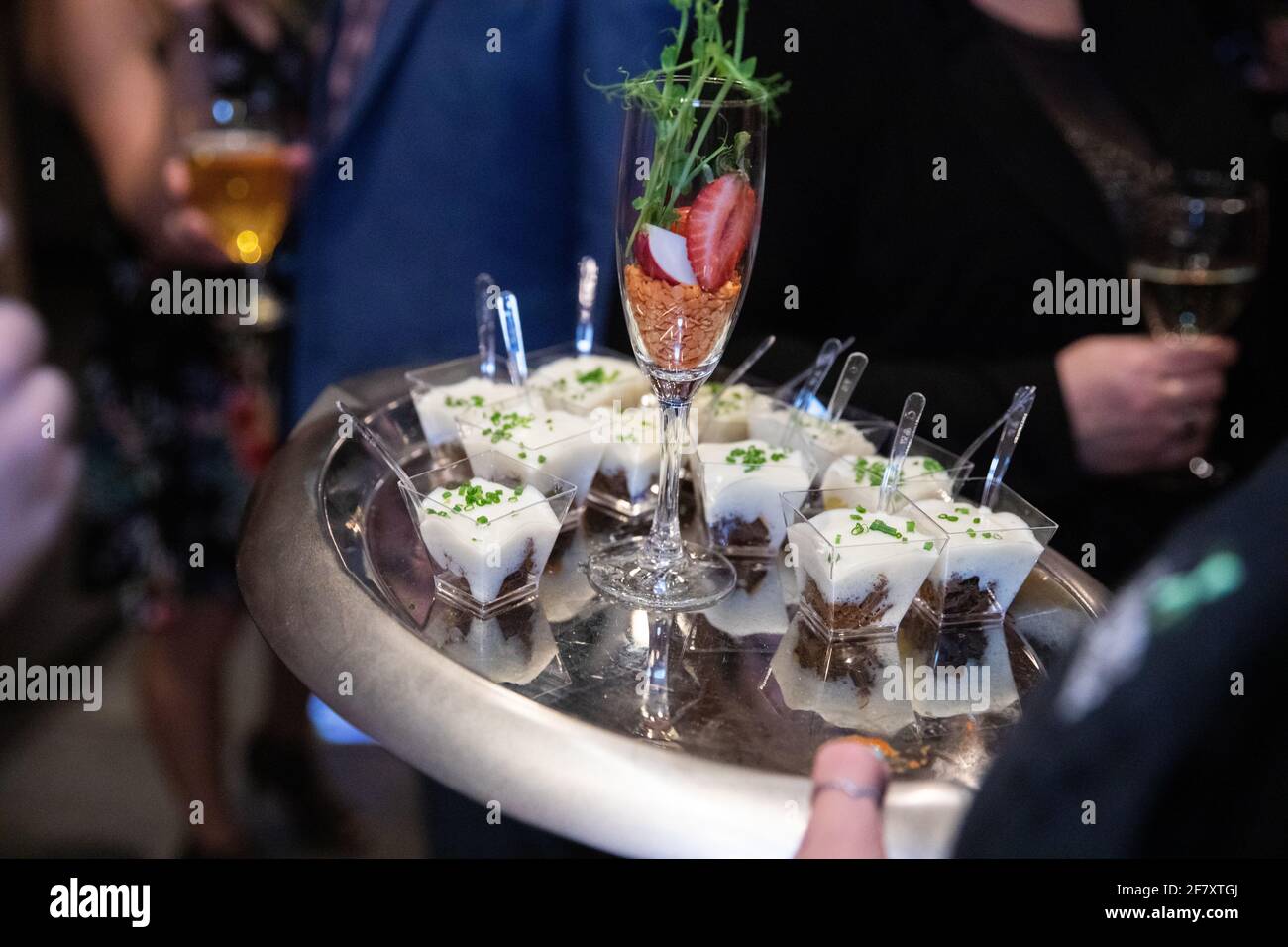 Garçon tenant une assiette remplie de petits doigts de nourriture dedans petites tasses avec fourchette le soir Banque D'Images