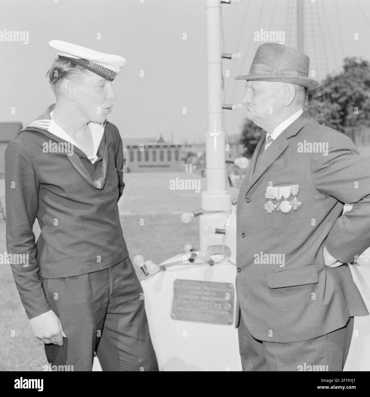 Sur le quai pour les casernes de services sous-marins, le service sous-marin (OZD) reçoit une bannière pour apprécier la performance livrée pendant la Seconde Guerre mondiale (WW2). Bien sûr, qui est décerné par la reine Juliana, 2 promotions: Mer de Chine du Sud 1941-'42 et Mer Méditerranée 1941-'42. La 4e classe militaire de Willems (MWO4) décernée en 1947 est également confirmée. Un jeune membre de l'OZD en conversation avec un réuniste à la tour de commandement de HR.Mme Bateau de torpille sous-zée n° 1 (Luçon et Emergo) (HR.Mme O1) (1906-1920). Banque D'Images