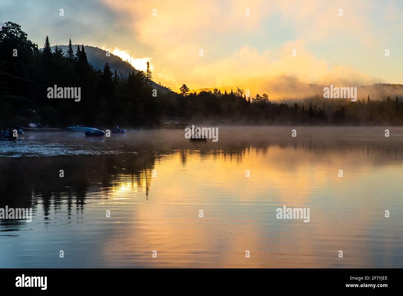lac calme au lever du soleil avec un jouet gonflable la distance avec ciel lumineux et jaune Banque D'Images