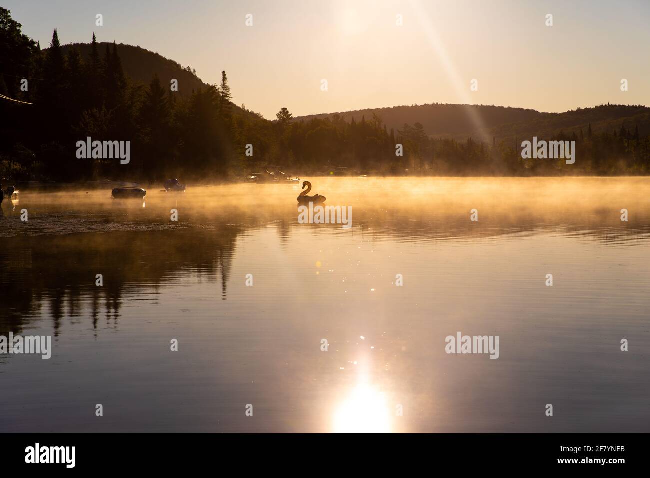 jouet gonflable dans la distance sur un lever de soleil lumineux avec le soleil se reflète dans l'eau Banque D'Images