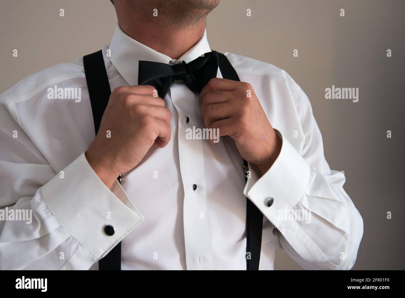 Homme vêtu d'une chemise blanche avec bretelles noires resserrées son noeud  papillon Photo Stock - Alamy