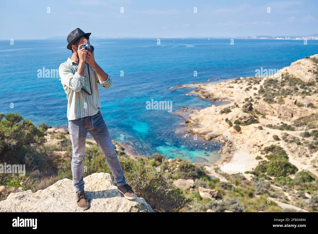 Un jeune touriste prend une photo du sommet d'une colline où vous pouvez voir la mer avec de belles couleurs, il porte un regard très frais Banque D'Images