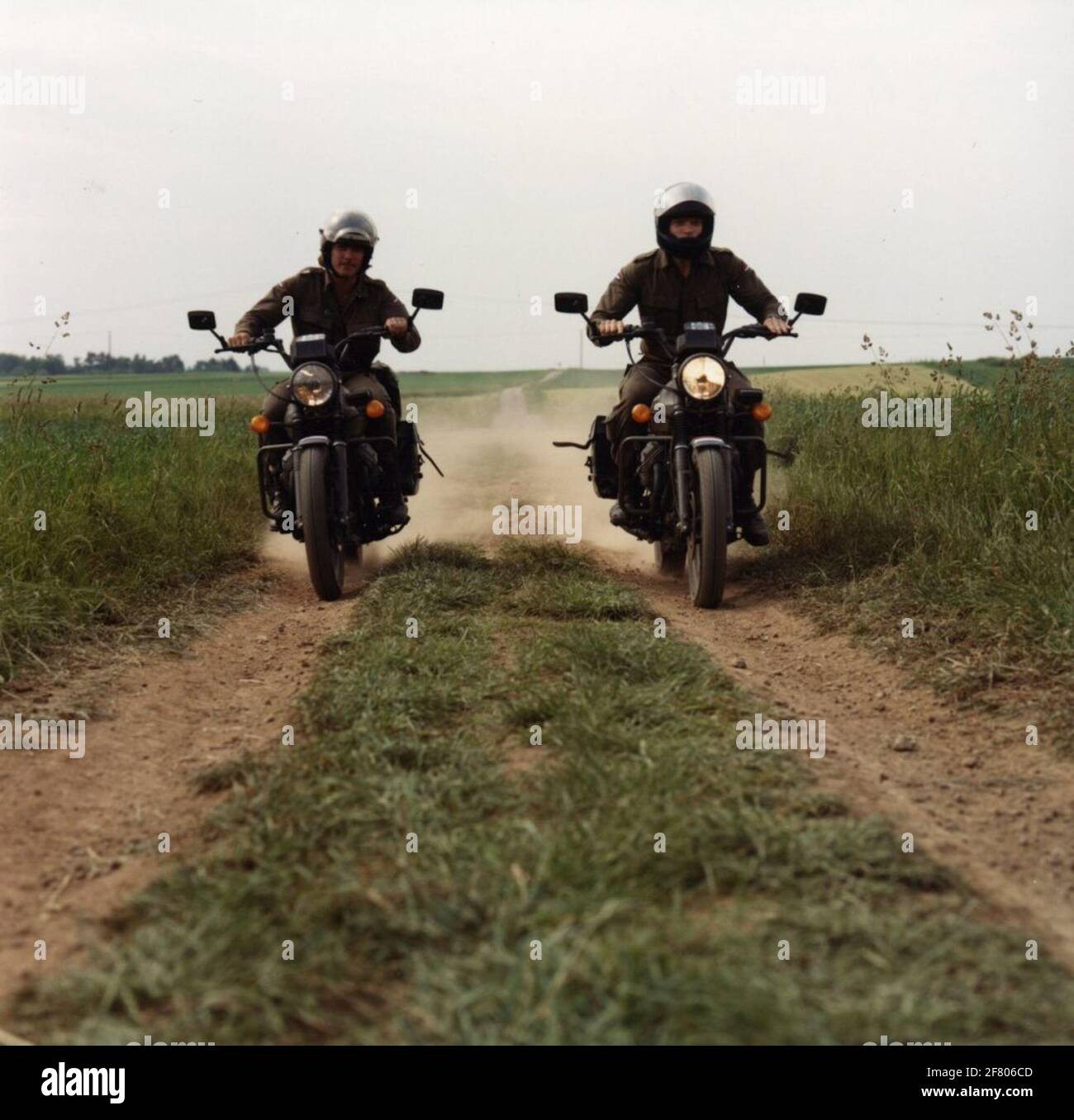 Deux motos dansant côte à côte, chacune sur une moto 'Moto Guzzi V 50' sur  Zandweg, frontally photographiée. Photo faite sur le 'Kylerhöhe' à  Hillesheim, Allemagne pendant l'exercice 'Anijflelag 'du 12 Painbrig