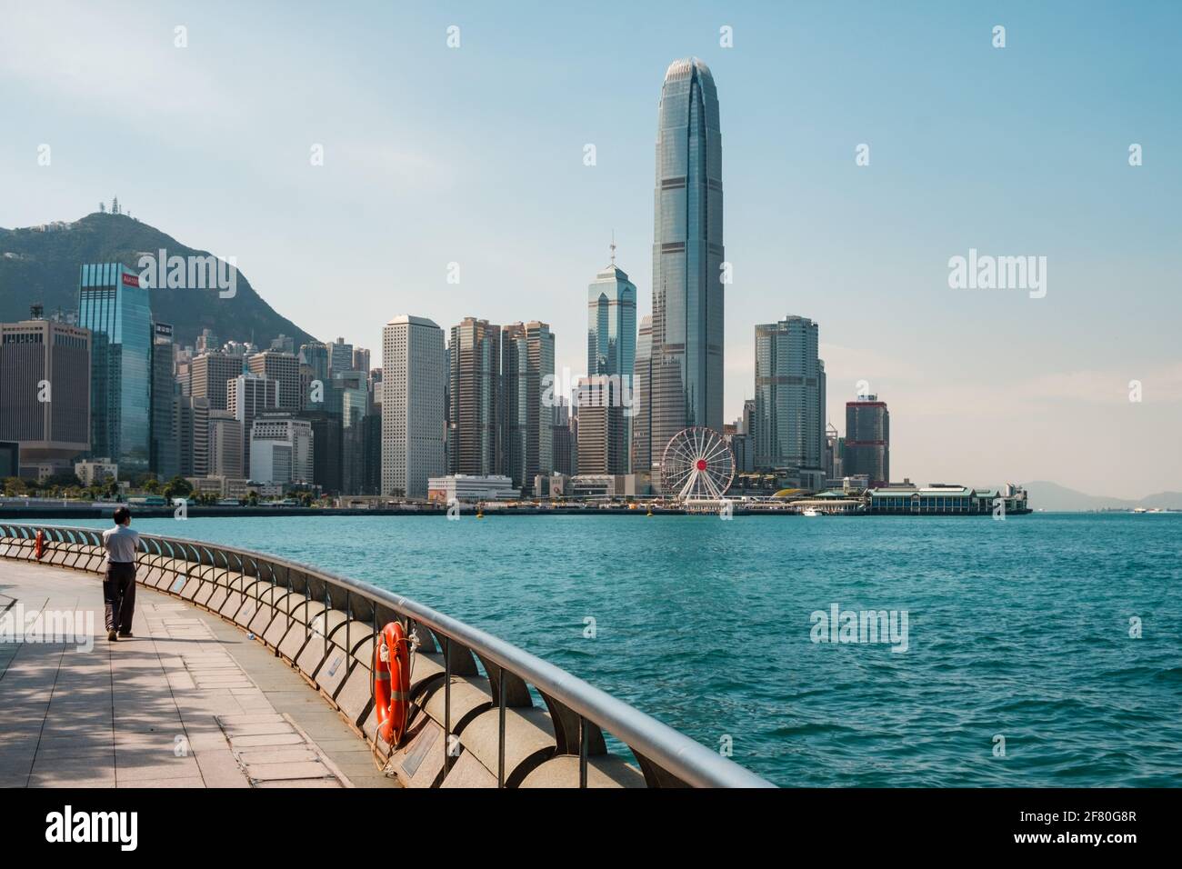 Hong Kong, Chine - Novembre 2019 : personne marchant à promenade au bord de l'eau avec le port de Victoria et les toits de l'île de Hong Kong en arrière-plan Banque D'Images