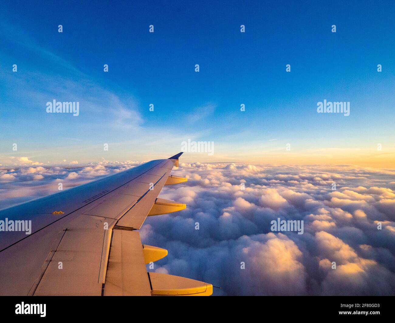 Ailes d'avion sous le lever du soleil avec des nuages en dessous Banque D'Images