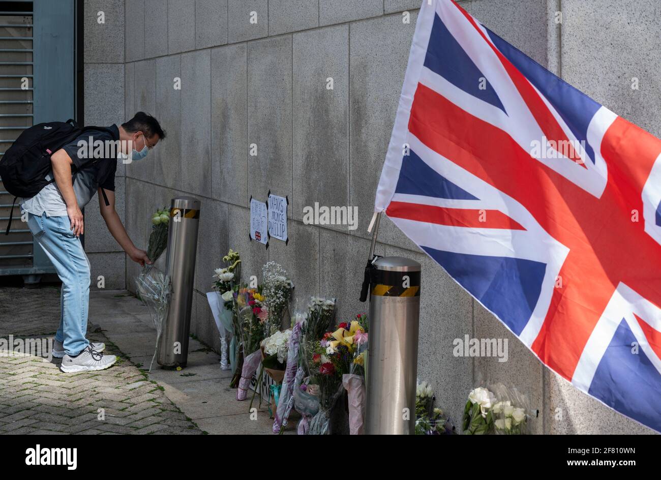 Un pleurant dépose des fleurs devant l'ambassade Consulat général britannique de Hong Kong après l'annonce de la mort du prince Philip de Grande-Bretagne à Hong Kong. Le prince Philip, mari de la reine Elizabeth II, est décédé à l'âge de 99 ans. Banque D'Images