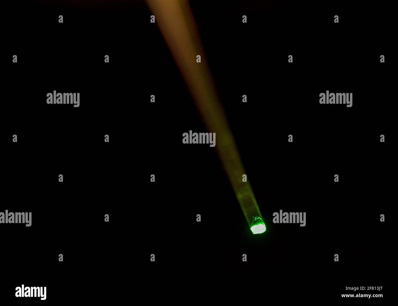 Fibre optique en plastique transmettant une lumière verte sur un fond sombre, illustrant la transmission de lumière par fibre optique et la technologie optique Banque D'Images