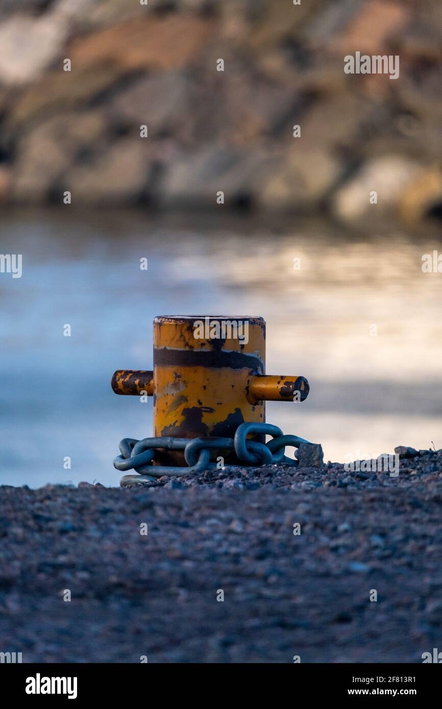 Helsinki / Finlande - 10 AVRIL 2021 : gros plan d'un bollard jaune avec une chaîne métallique attachée à celui-ci. Banque D'Images
